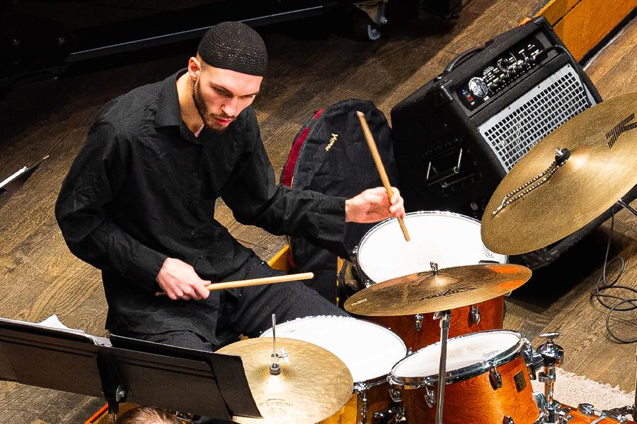 A member of the jazz band plays snare drums and cymbals.