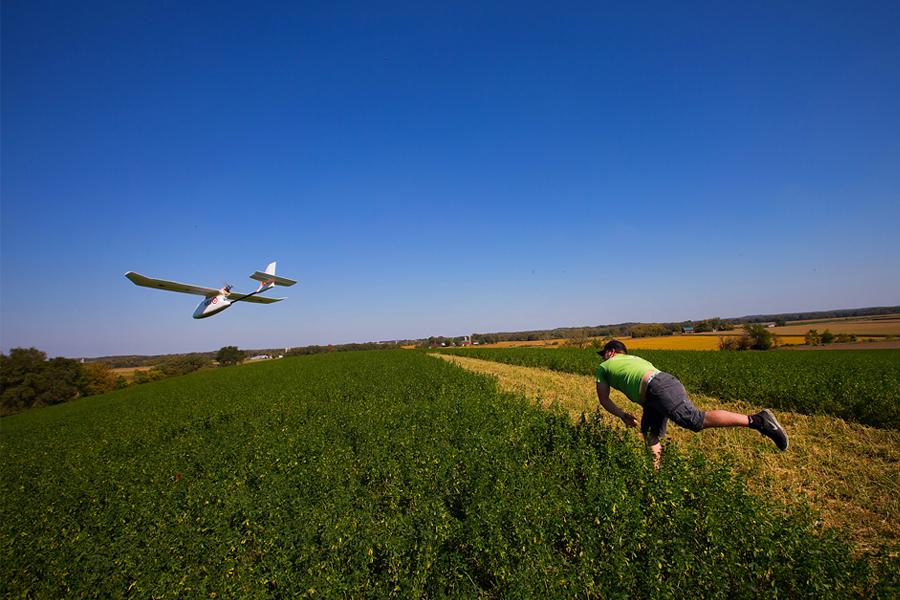 A student throws a mapping drone in a field.