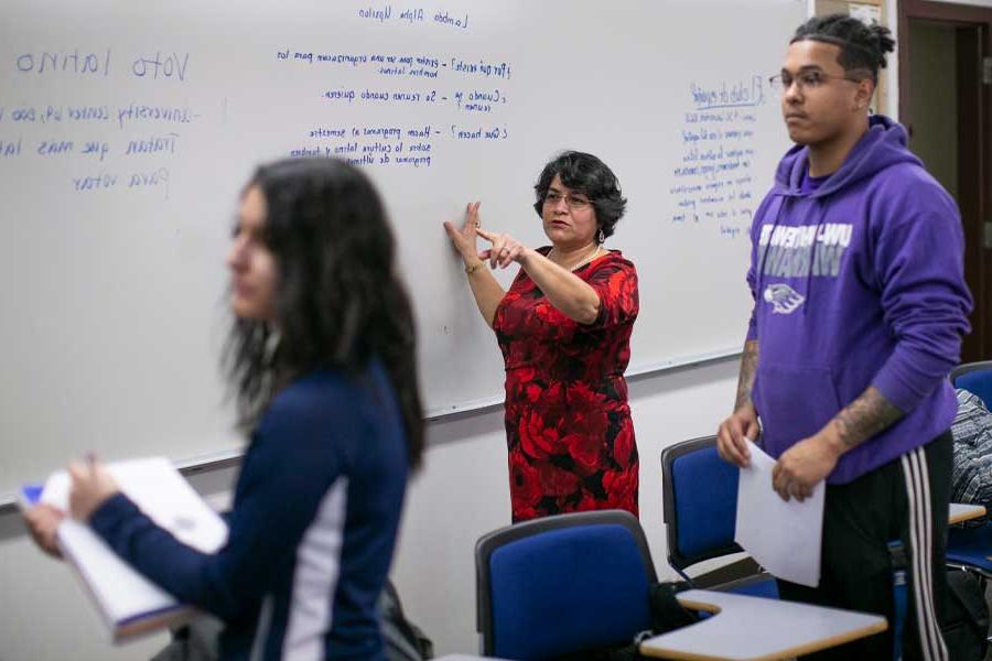 A Spanish faculty member teaches at a whiteboard.