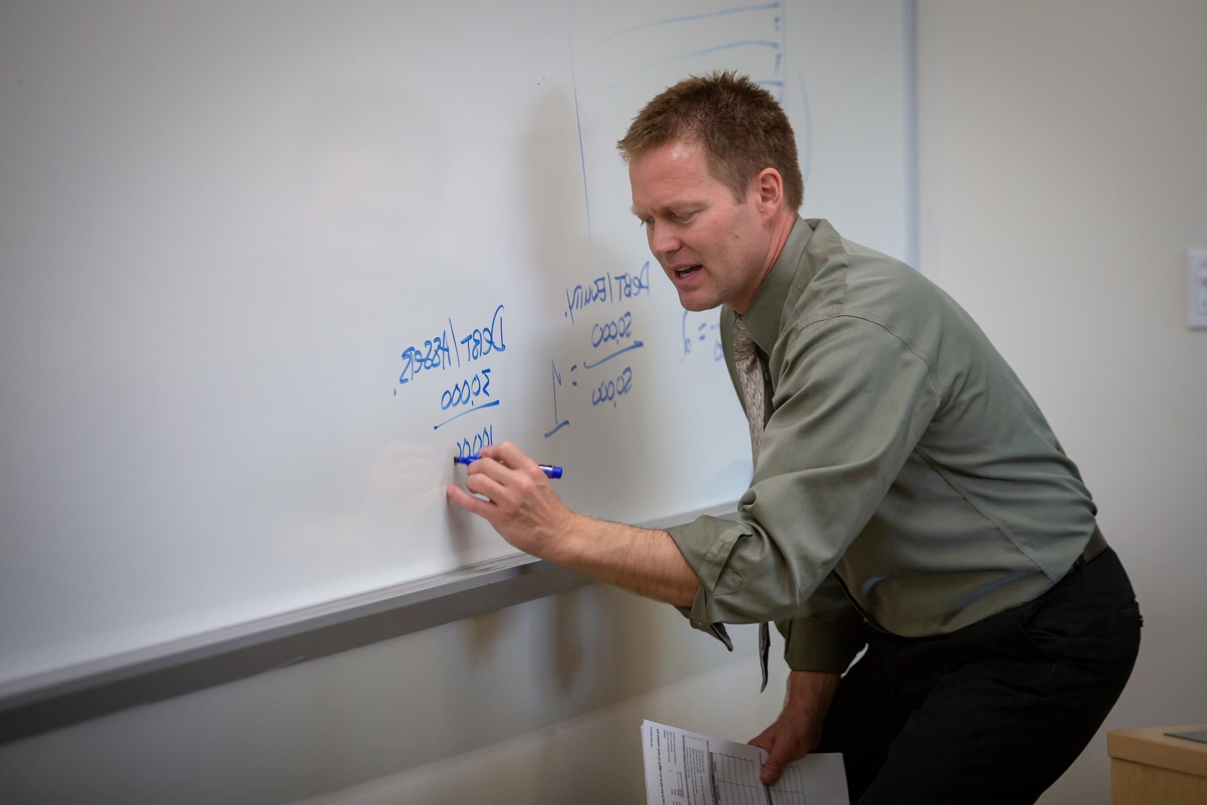 Professor writing on whiteboard