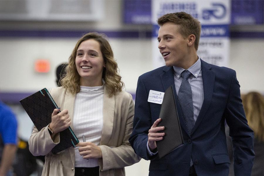 Two students wear professional attire as they walk together.